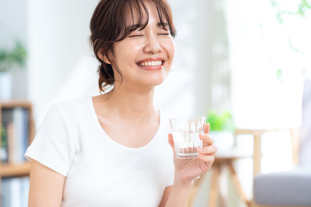 ウォーターサーバーの水を手にして笑顔の女性